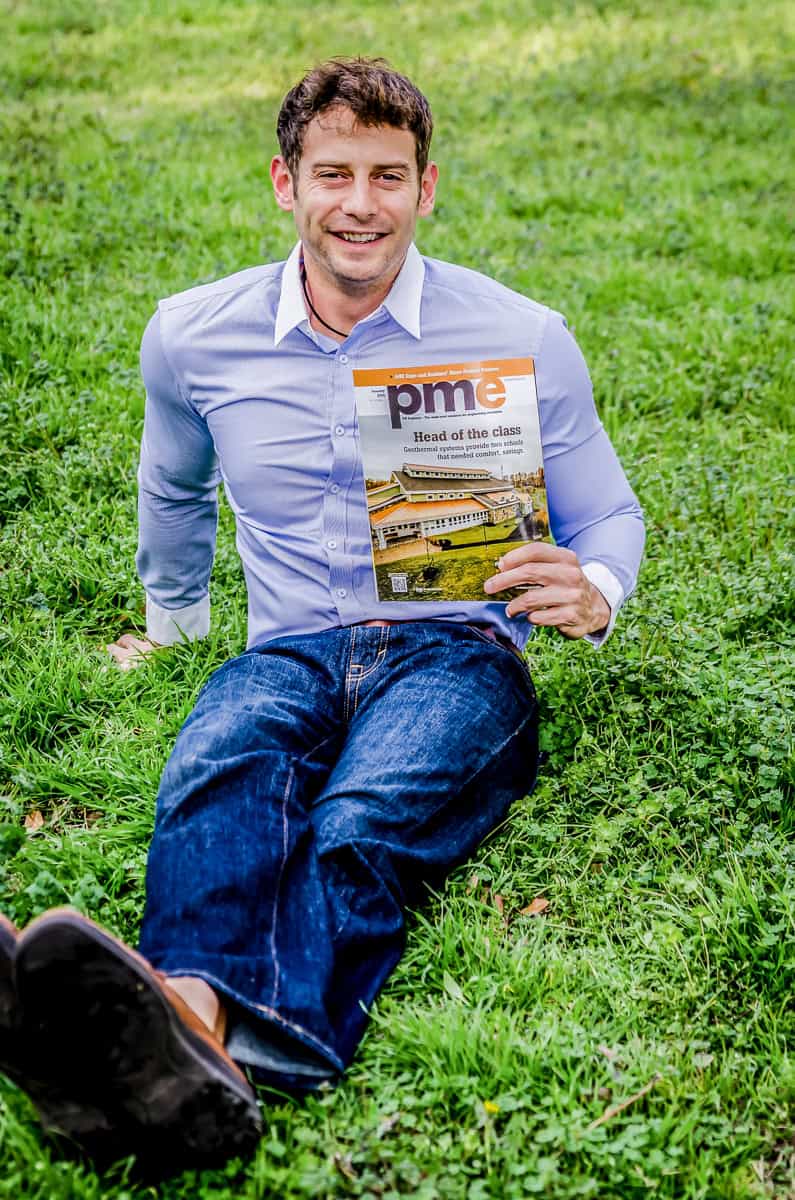 A man laying on the grass holding a magazine.