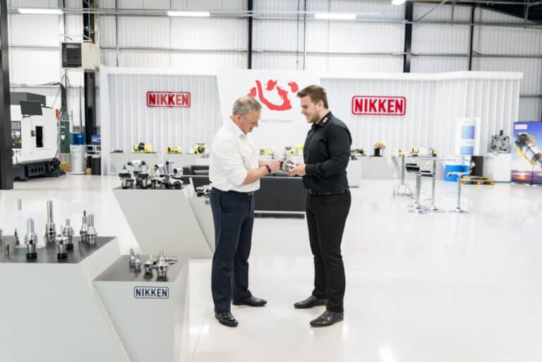 Two men standing in front of a machine shop.