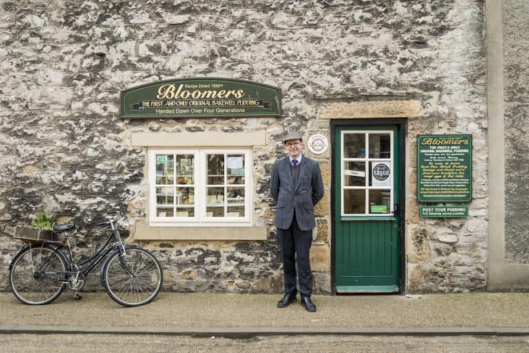 A man in a suit standing in front of a stone building.