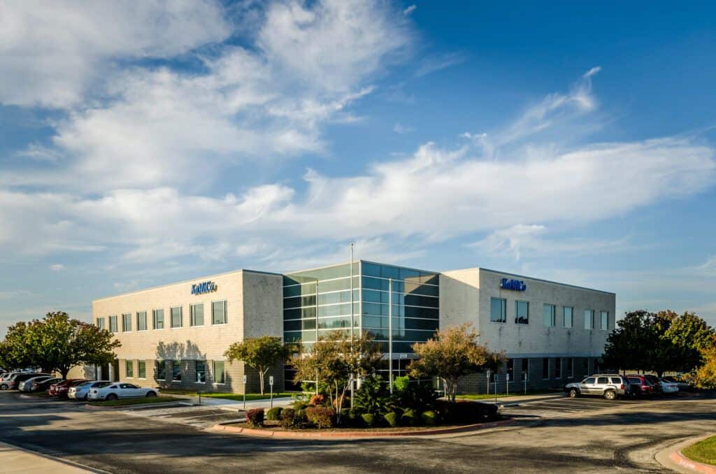 A large office building with cars parked in front of it.