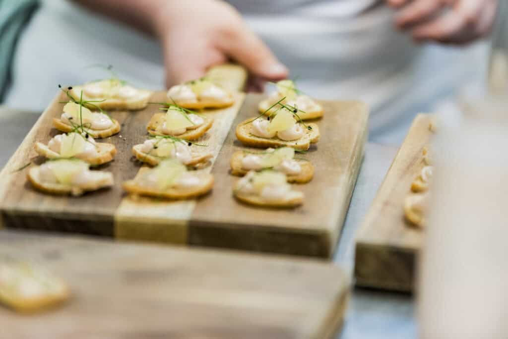 A person is preparing some appetizers on a wooden board.