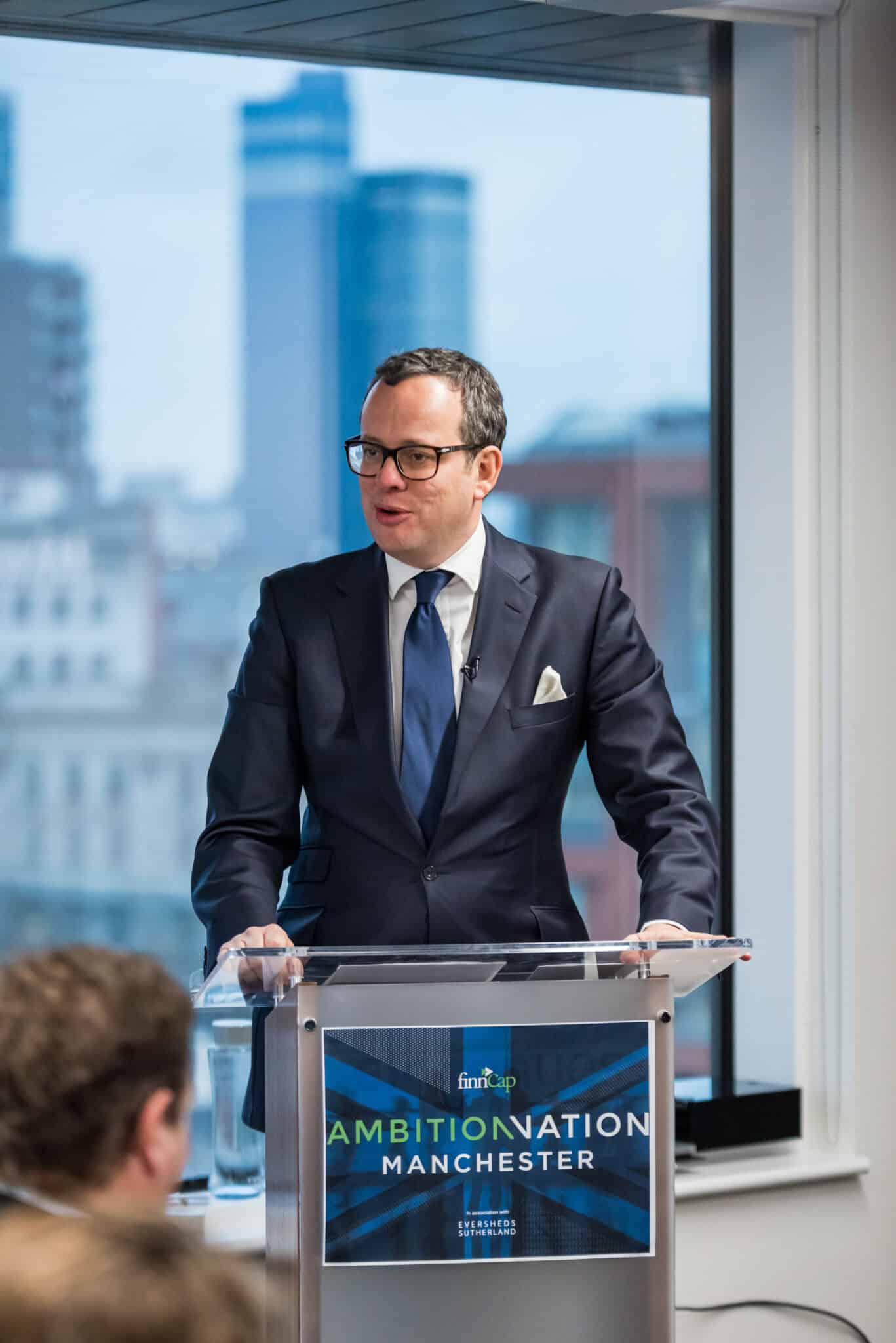 A man in a suit standing at a podium.