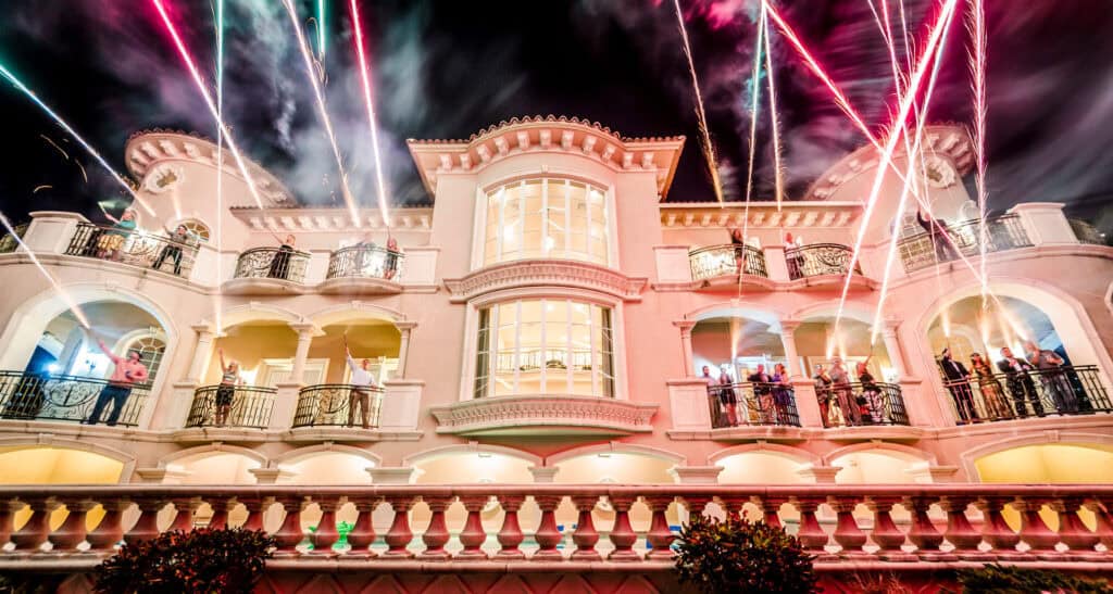 A large mansion is lit up with fireworks.