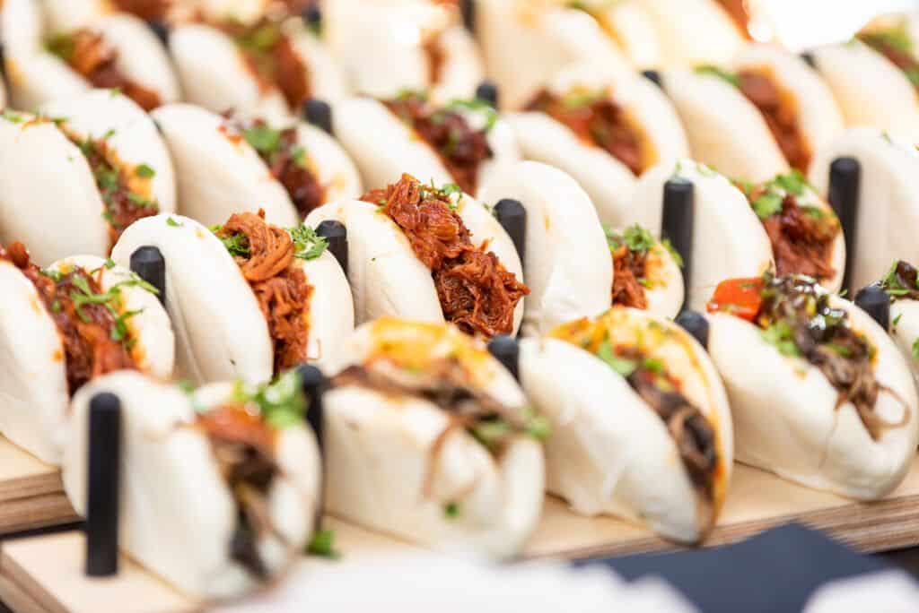 A tray of pork buns on a wooden tray.