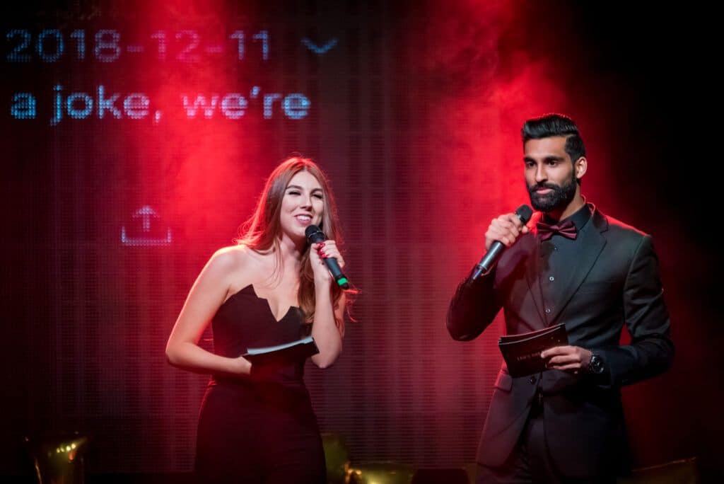 A man and woman standing on stage with a microphone.