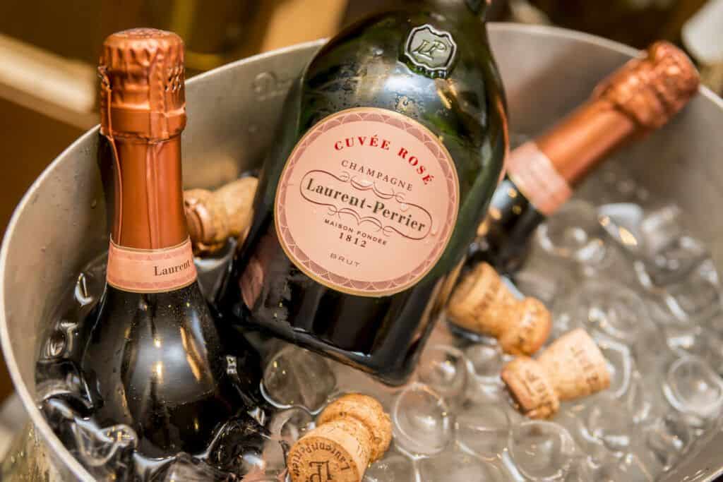 Two bottles of champagne sitting in a bucket of ice.
