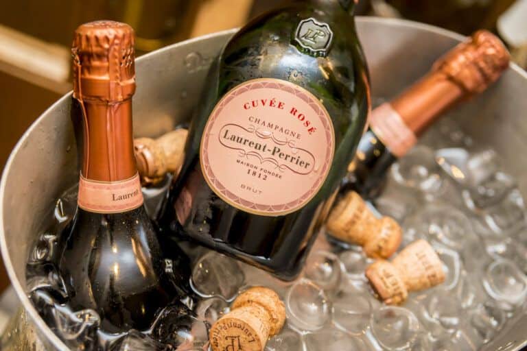 Two bottles of champagne sitting in a bucket of ice.