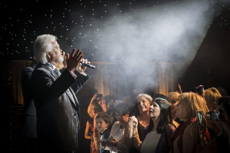 A man singing into a microphone in front of a crowd.