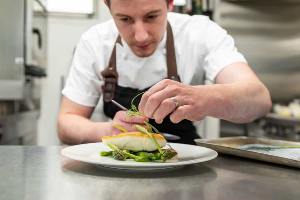 A chef preparing a plate of food in a kitchen.