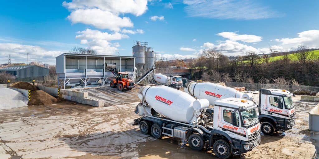 Two cement mixer trucks parked next to each other.
