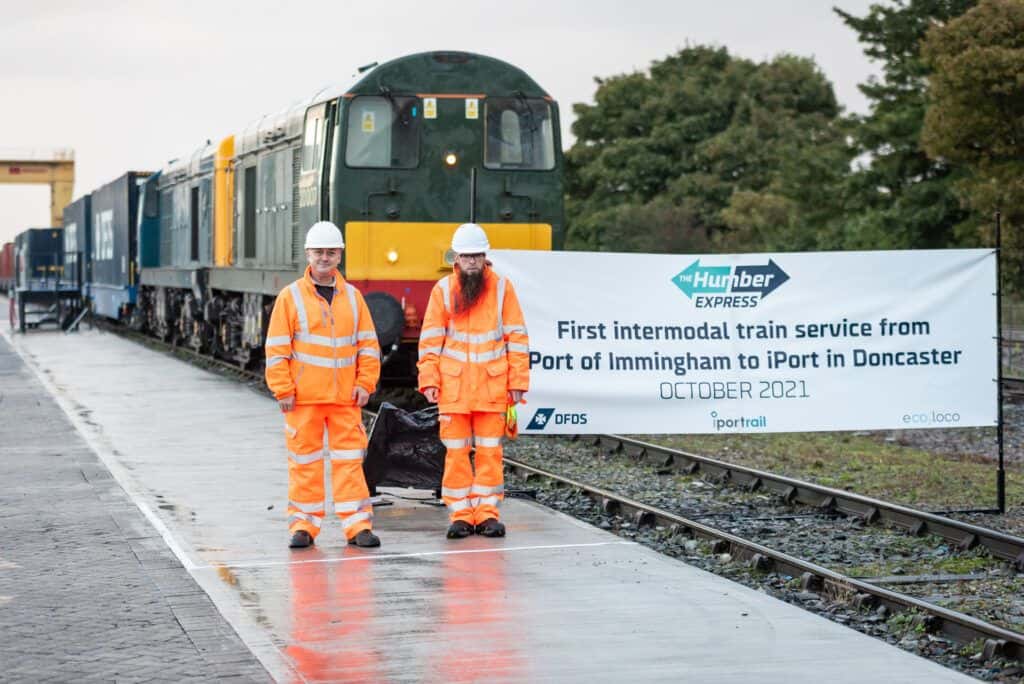 Two men standing next to a train.