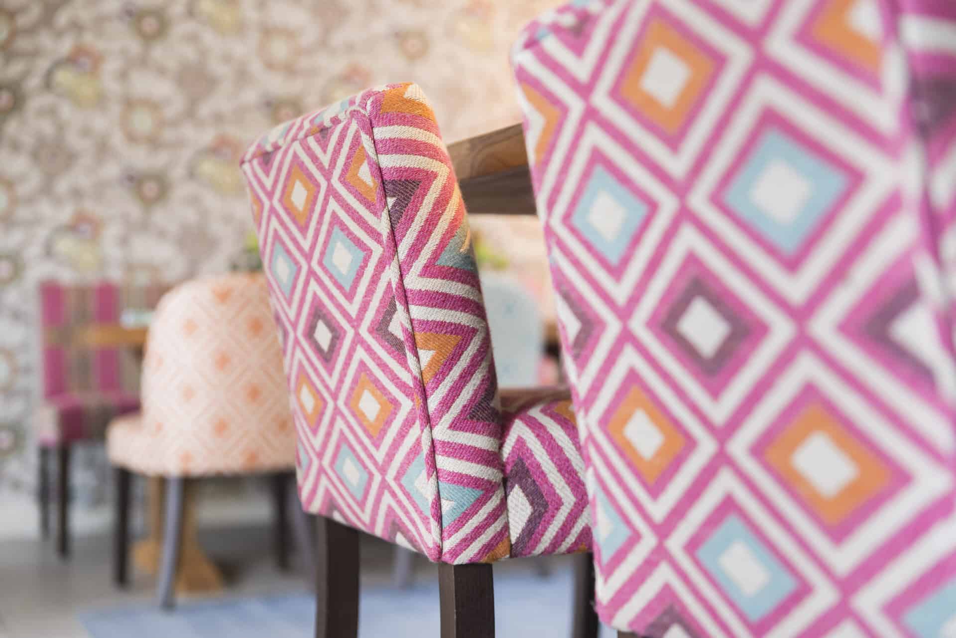 Chairs in a dining room with colorful patterned upholstered backs.