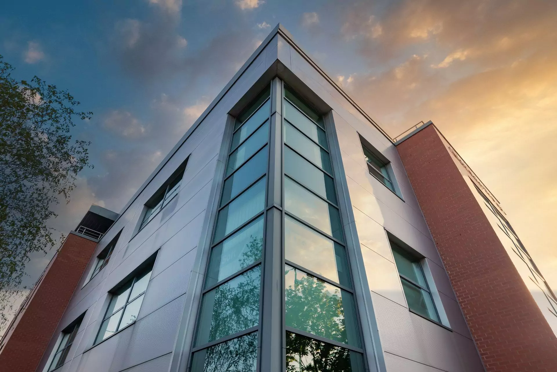 Modern office building photographed at golden hour with warm evening light on the glass
